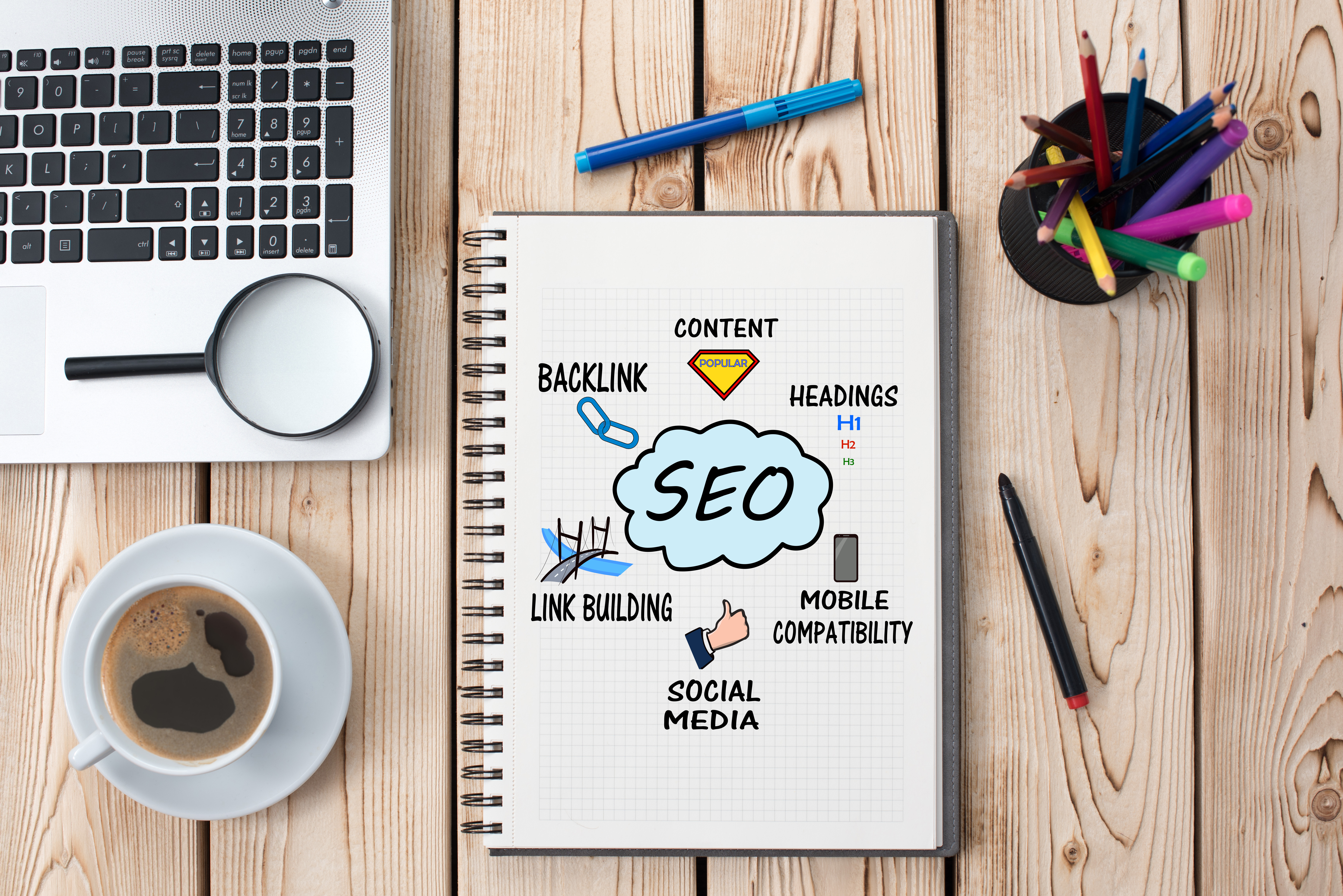 the words search engine optimization on a notebook with more words saying content,headings, mobile compatibility, social media, anmd link building